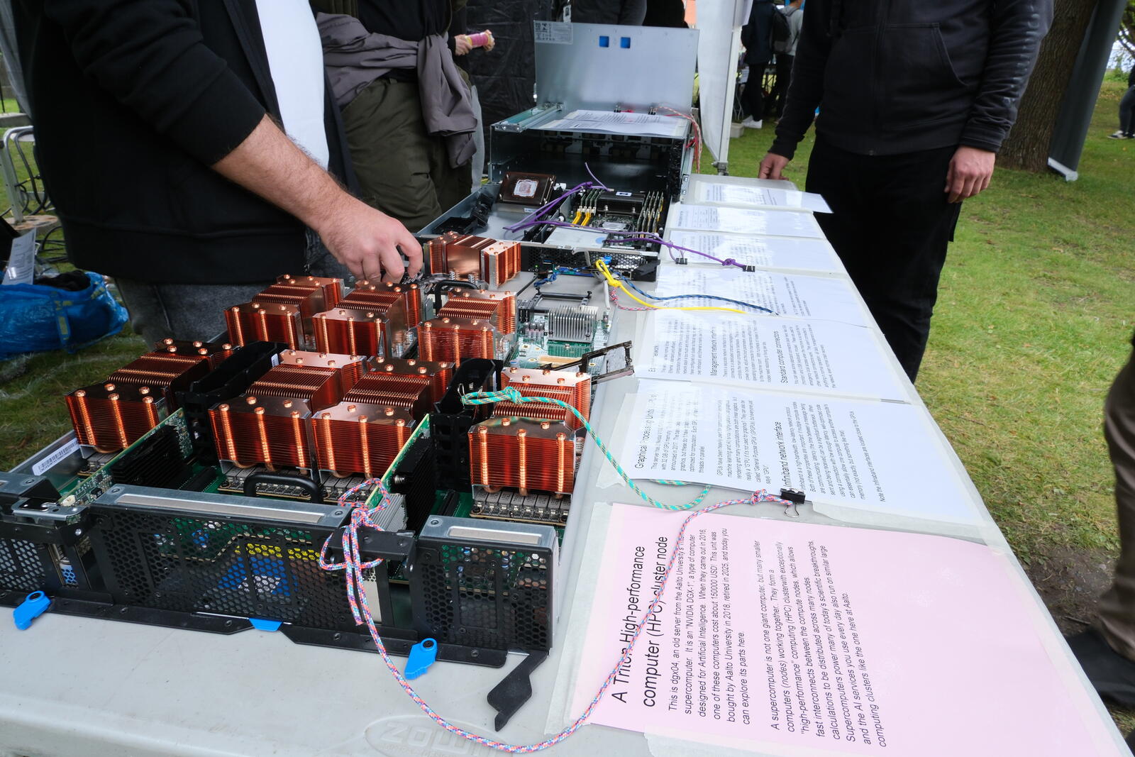 Visitors examining the open dgx04 server and its copper GPU heatsinks at the Aalto Day One 2025 booth